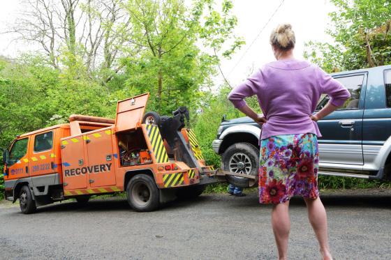 Woman in purple watching car get towed